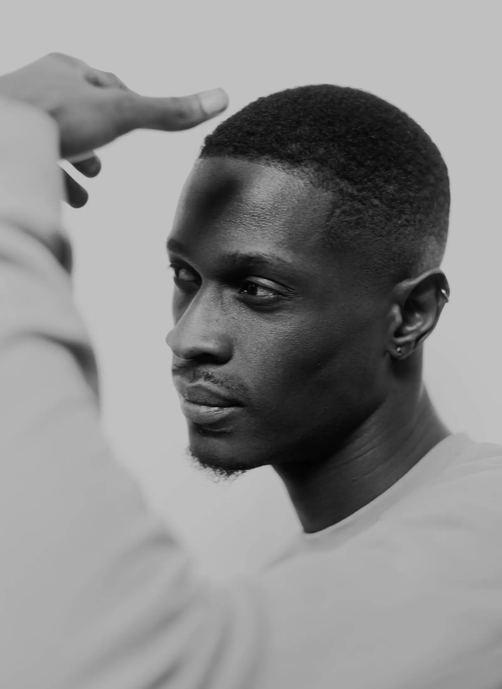 Portrait en noir et blanc d'un homme de profil qui passe la main au-dessus de son front, près de la ligne des cheveux.