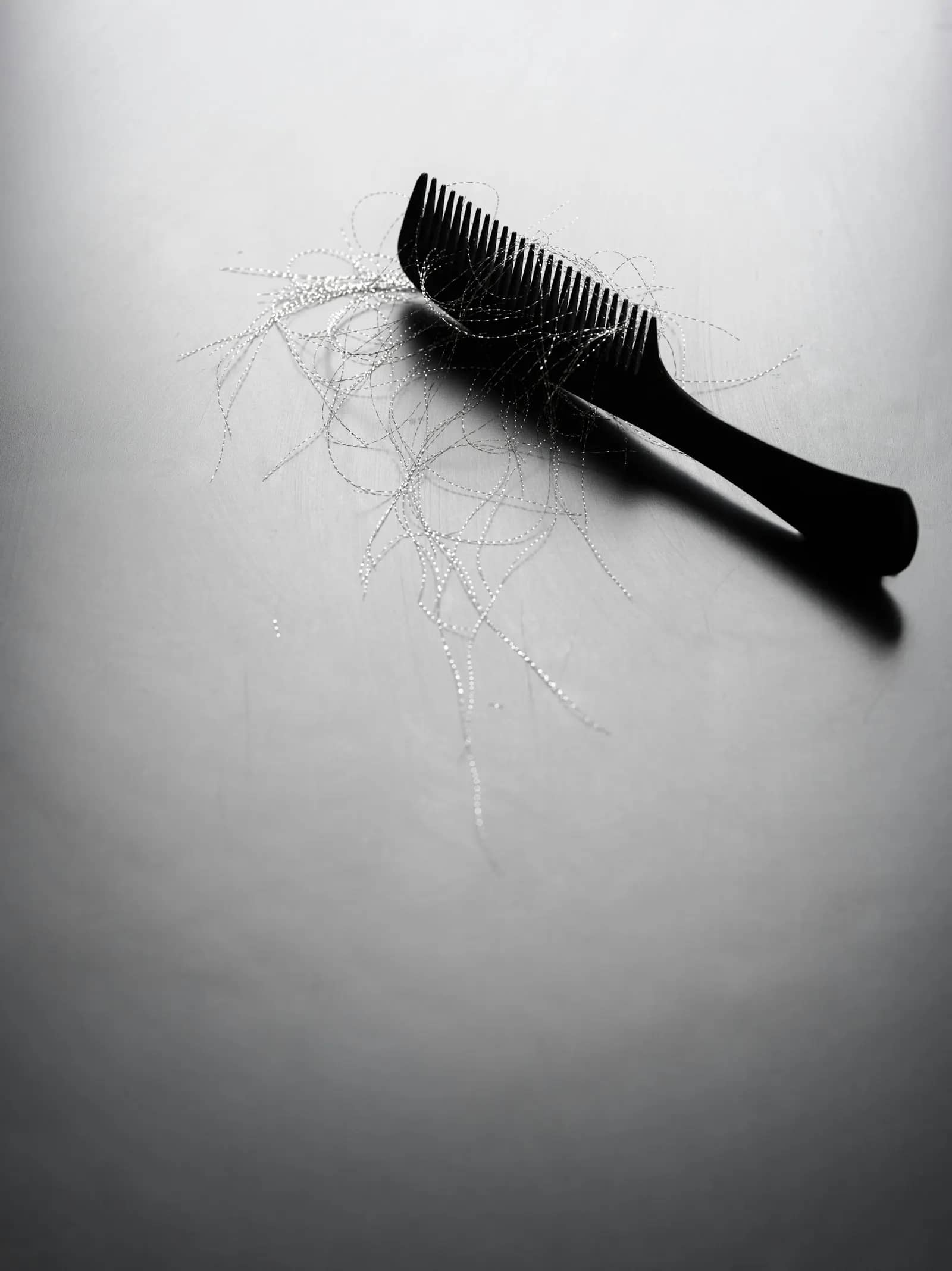 Peigne noir posé sur une surface claire, entouré de quelques cheveux tombés.